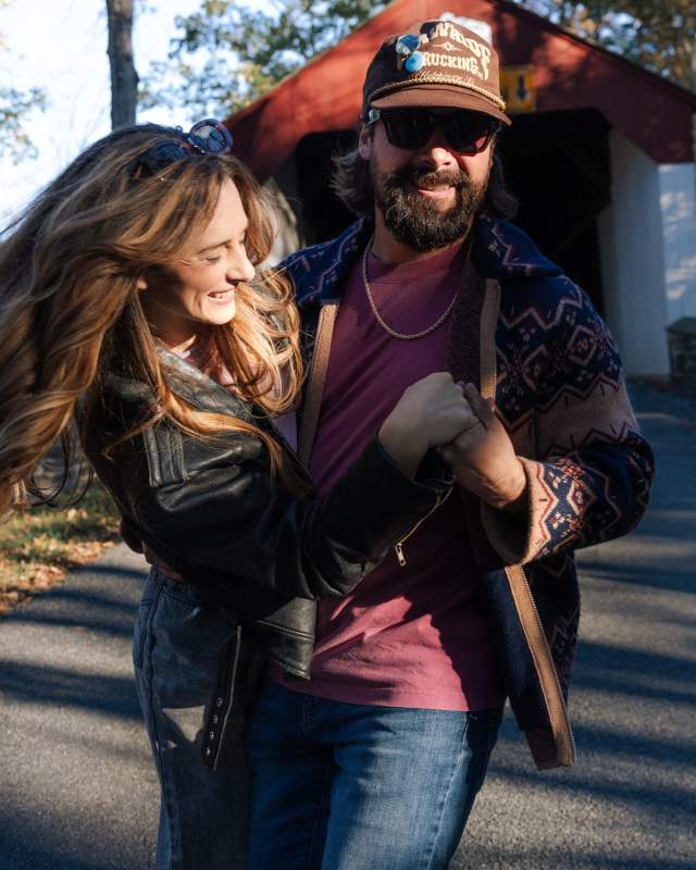 A man and woman hugging while walking on a paved road of a covered bridge