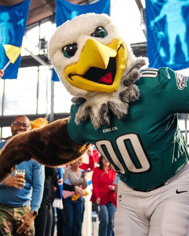 The Eagles football team mascot, a bald eagle in a green jersey with the numbers 00, dancing in a crowd