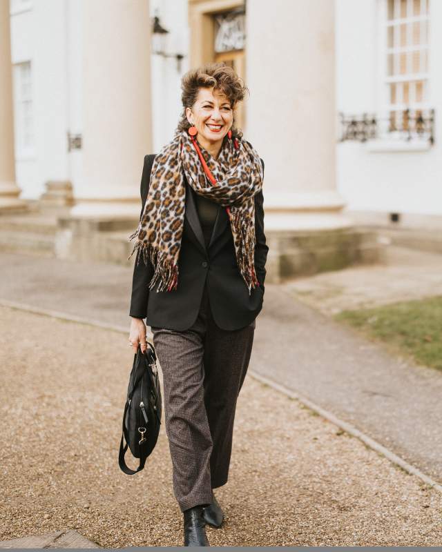 a woman walking along a path outside a white building with pillars