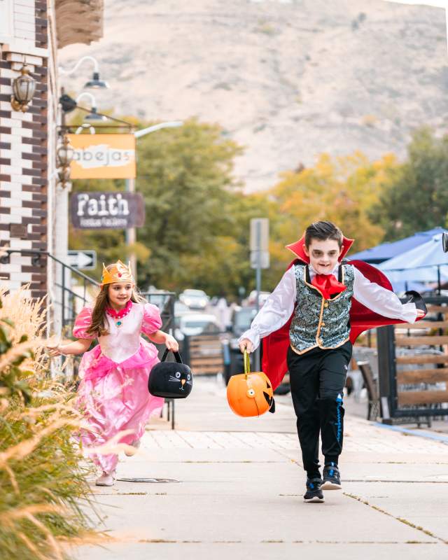 Kids dressed in Halloween costumes running through downtown Golden