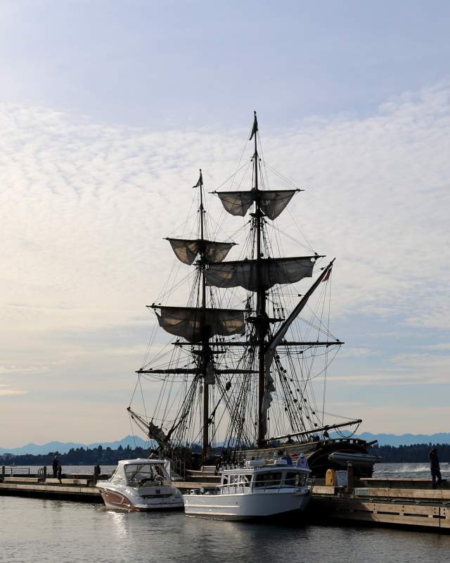 Tall ship at a dock with smaller boats in front