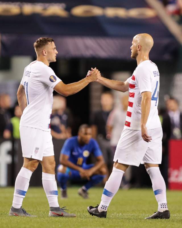 Two soccer players shaking hands on a soccer field.