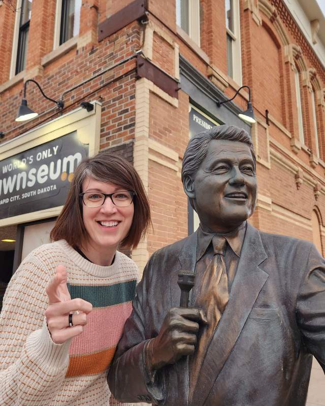 visitor posing with city of president statue found in downtown rapid city, sd