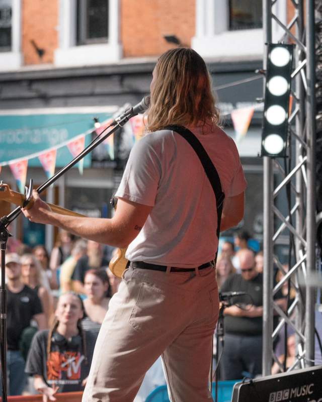 A live concert in Lincoln's Cornhill Quarter, a guitarist looks out over a crowd of people