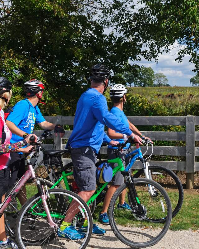 A group of road cyclists stop to watch a herd of Bison grazing at Battelle Darby Creek.