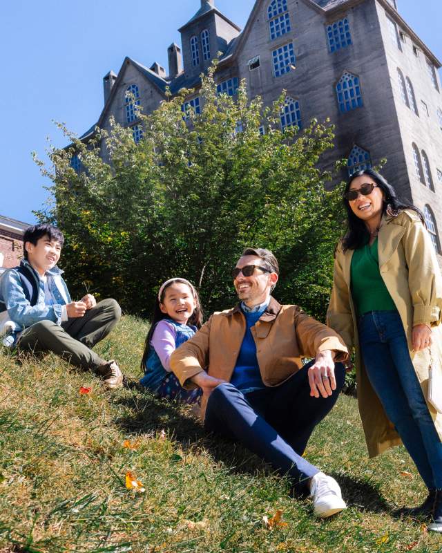 Family of four sitting on a hill in front of a castle