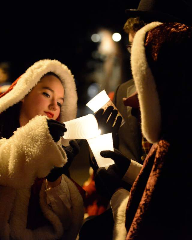 Woman lights candle during Olde Golden Candlelight Walk in Golden, CO
