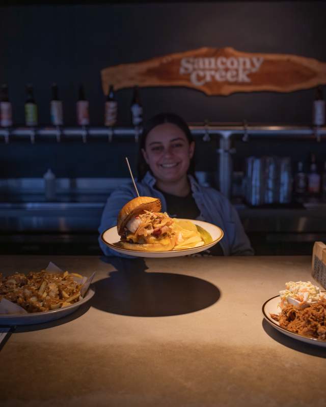 A burger is being served at the bar at saucony creek brewing with a side of fries in the background