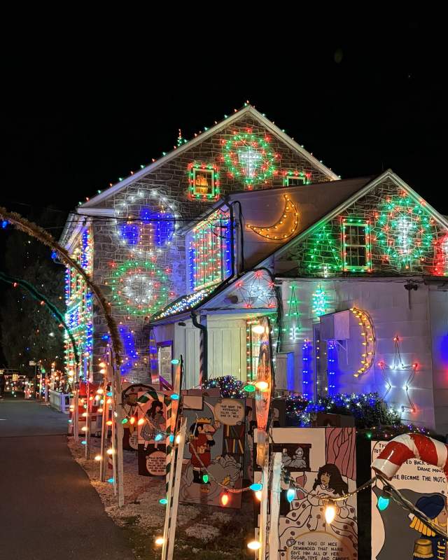House at Koziar's Christmas Village lit up with Christmas lights with a snowman in the front