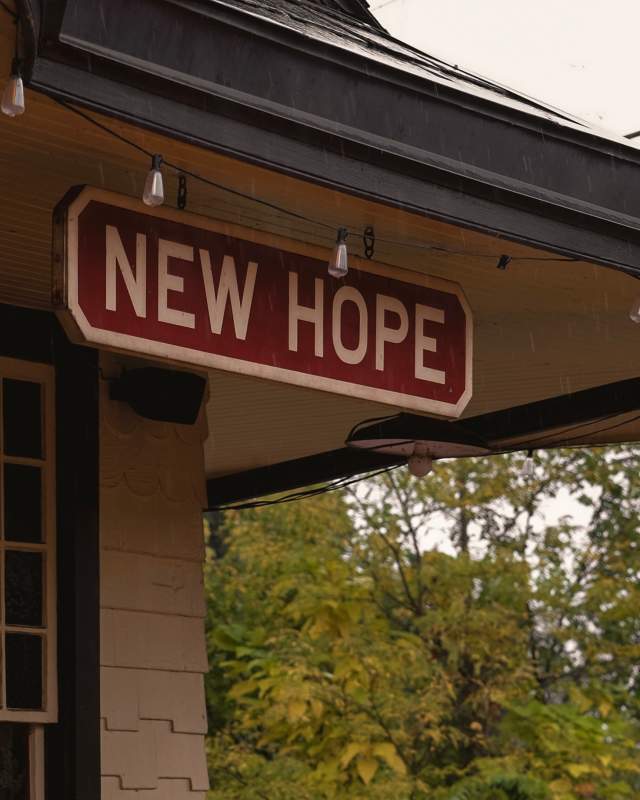 A sign at an outdoor train station that reads New Hope