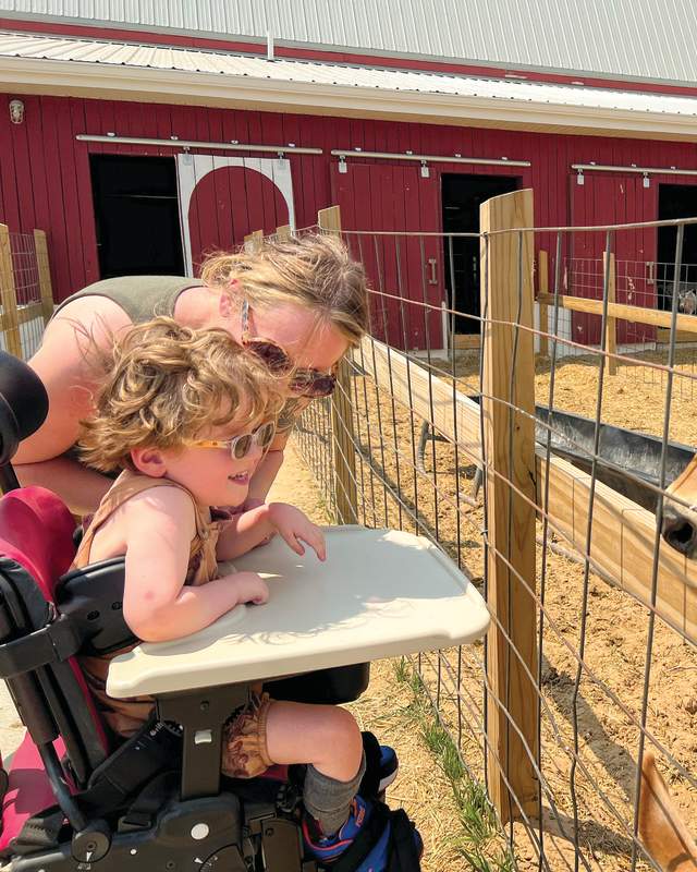 Small Child in Wheelchair enjoying animals at the Critter Barn