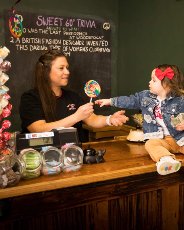 Little girl reaches for lollipop at Peppermint Stick Candy Store