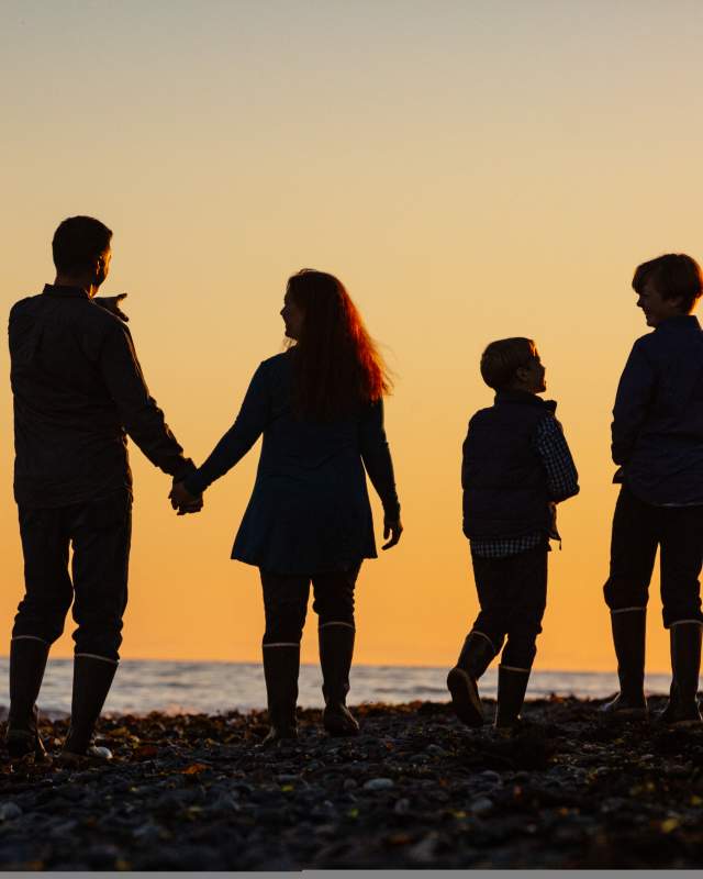 A family taking in the orange sunset at Kachemak Bay in Homer, Alaska on the Homer Spit