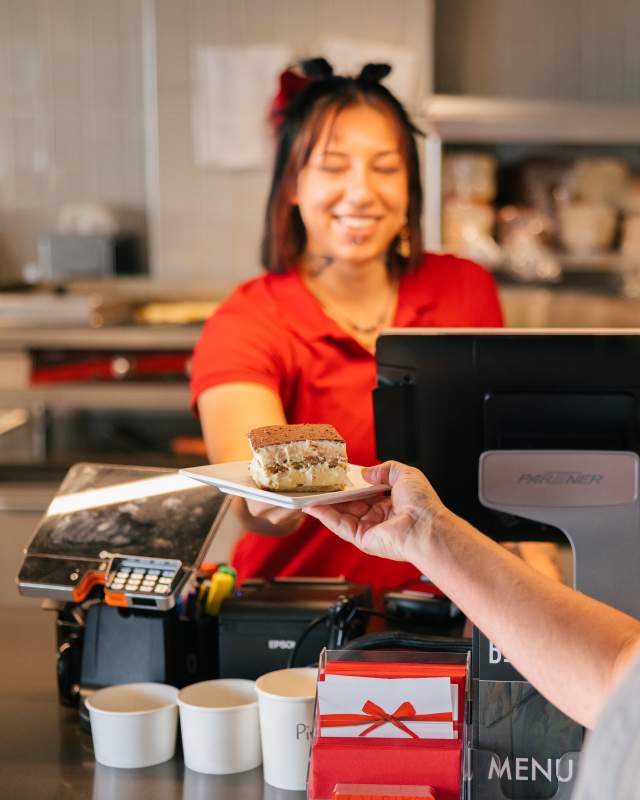 Woman behind the counter working at local lunch spot handing a desert to patron at The Bestro in Rapid City, SD.