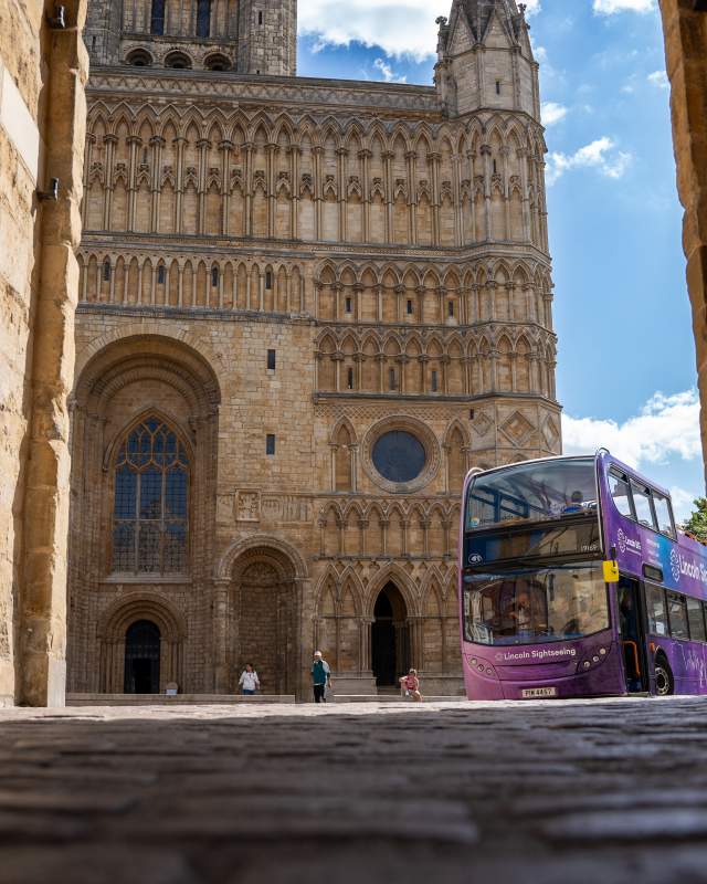 Open top tour bus outside of Lincoln Cathedral in sunlight