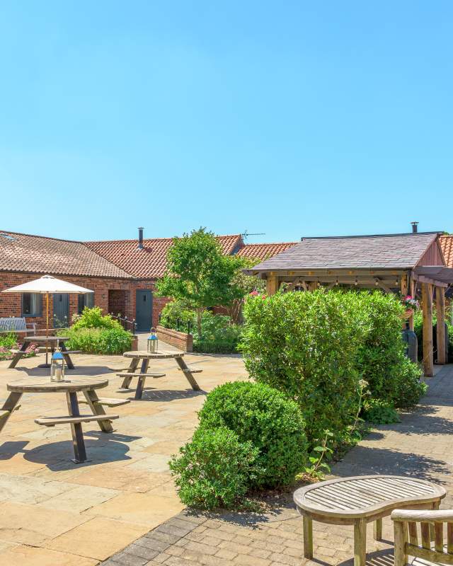 Holiday cottages courtyard area with plants and picnic tables