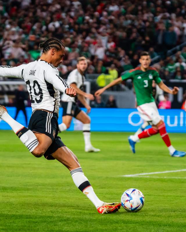 Man gearing up to kick a soccer ball during a match with people in Lincoln Financial Field stadium watching