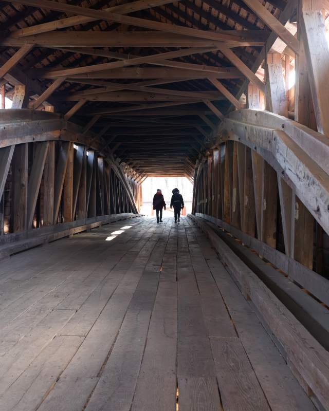 Two people walking through the covered bridge