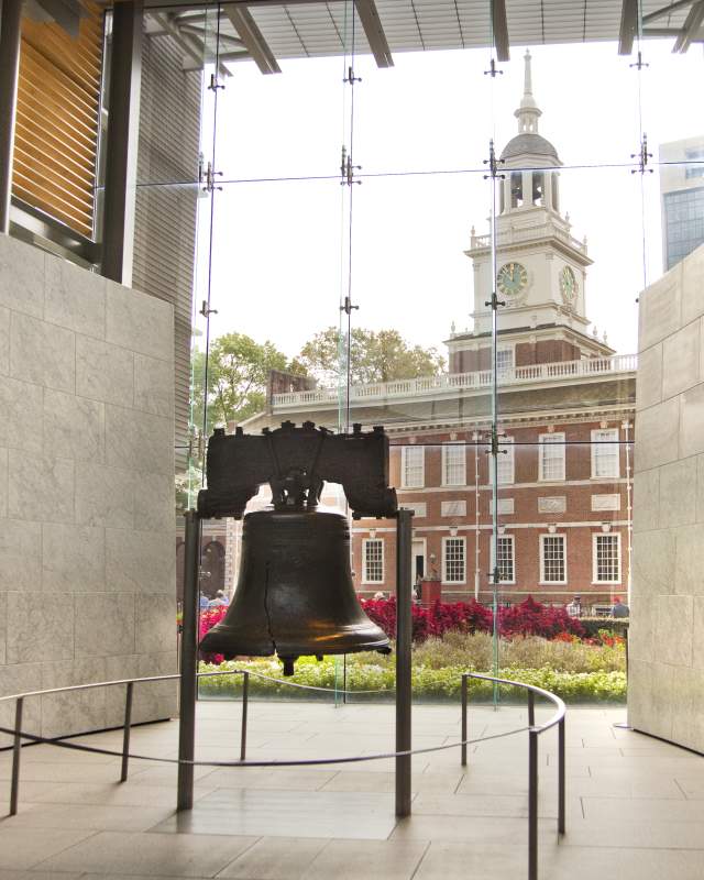 Large steel bell enclosed in a glass case in front of Independence Hall in Philadelphia