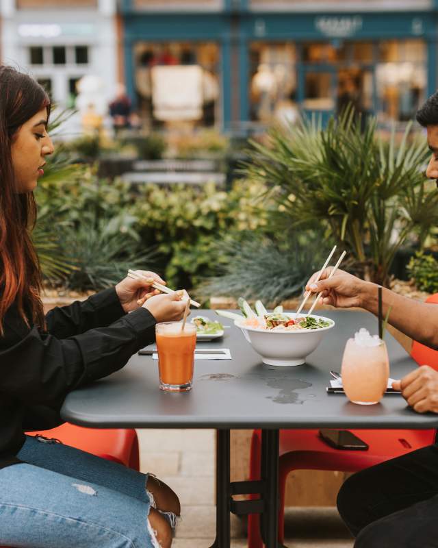 Two people enjoying a meal outside Pho.
