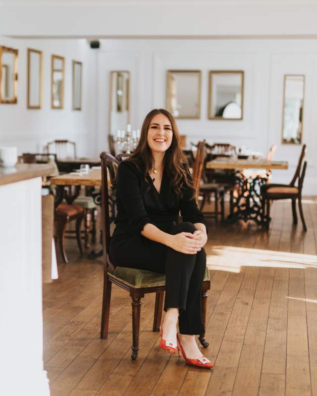 a woman sat on a chair in the centre of a restaurant space with cameras in the foreground