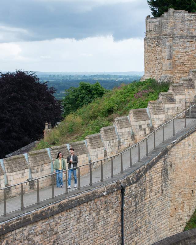 A couple walking along the Medieval Wall Walk at Lincoln Castle
