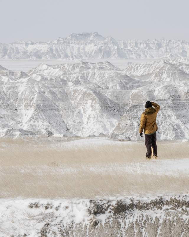 person exploring the beauty of badlands national park dusted in snow in the winter