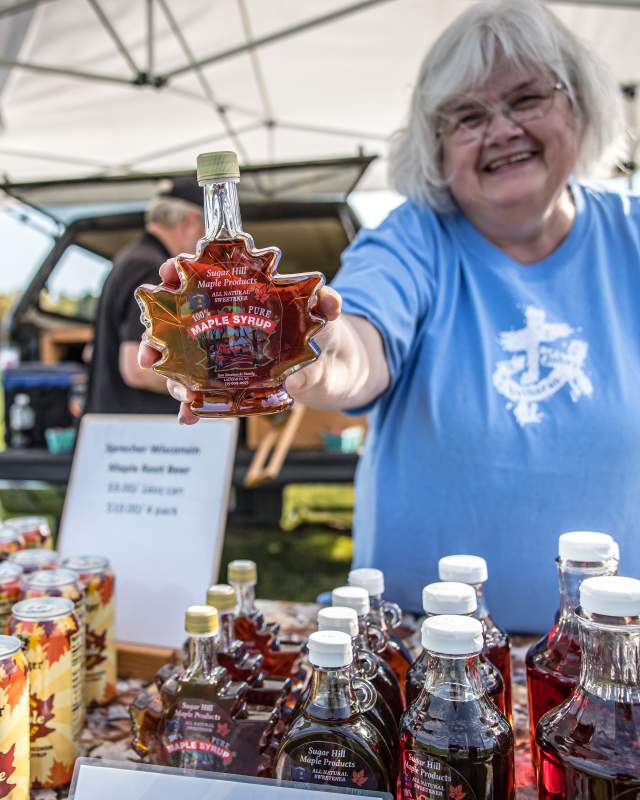 woman showing off maple syrup at farmers market