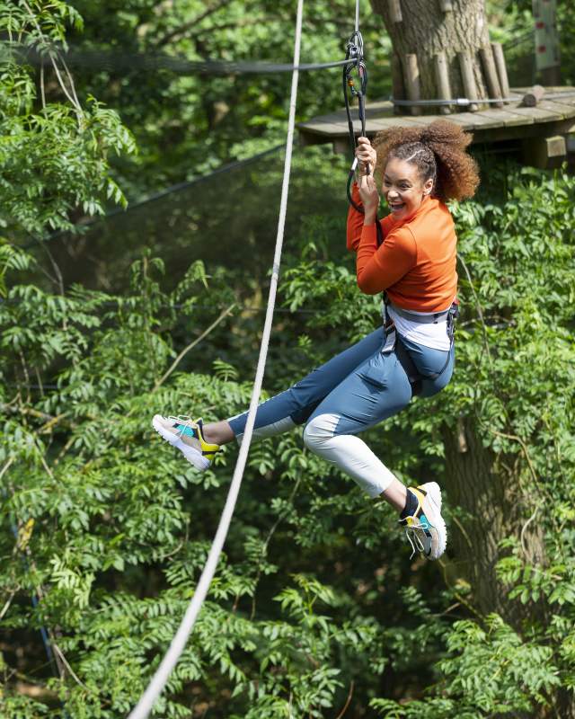 A girl soars through the trees on a zipwire at Go Ape Normanby Hall