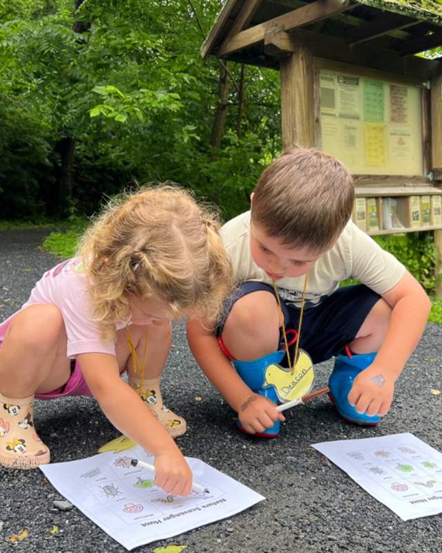 Two children outside in the park working on a scavenger hunt