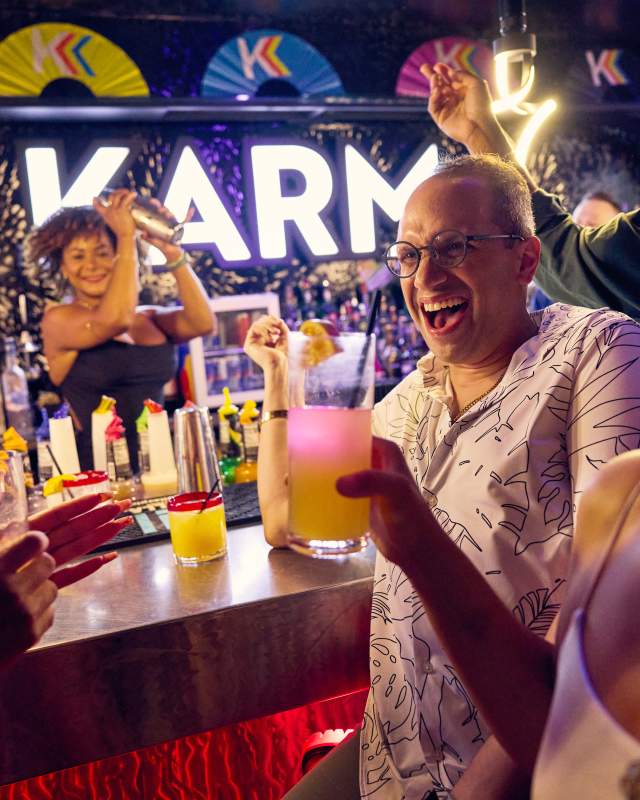 A group of friends gather with cocktails at the bar Karma in Harrisburg. The scene is lively and energetic.