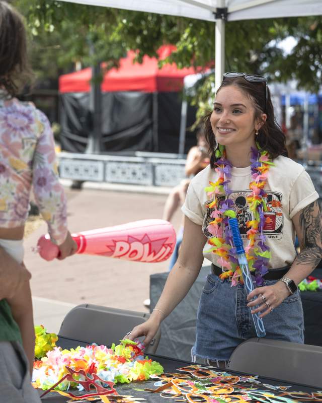 woman smiling behind booth at event attendees in Main Street Square, Rapid City SD