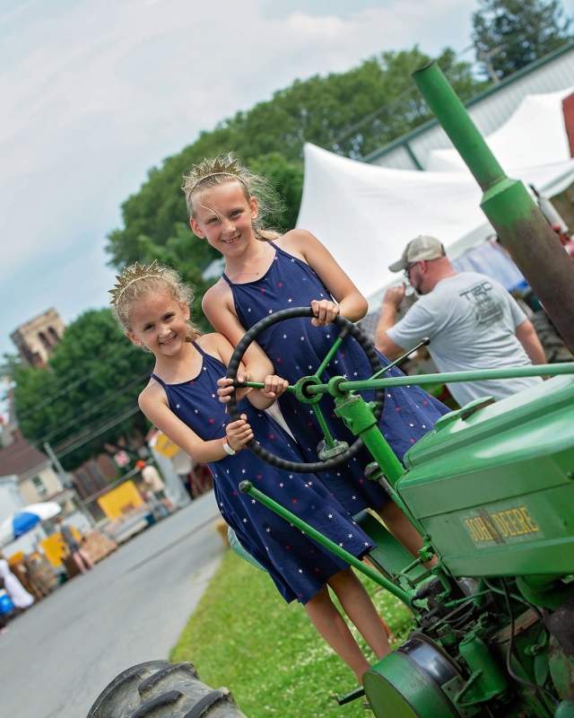 Little girls on a green tractor at the Kutztown Folk Festival