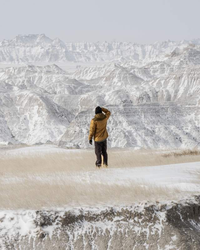 person exploring the beauty of badlands national park dusted in snow in the winter