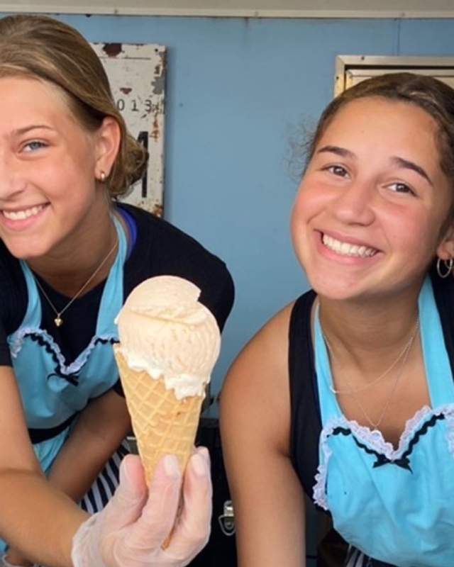 Two teenage girls serve ice cream from Sweet Ride's Ice Cream truck
