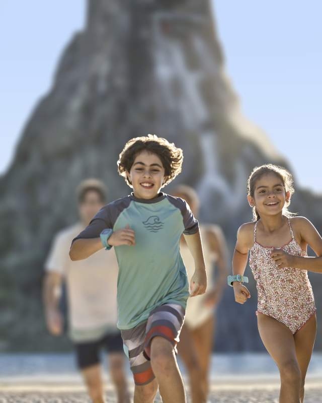 Kids in swim suits running ahead of their parents at Universal's Volcano Bay