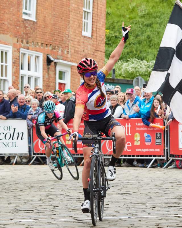 A female cyclist crossing the finish line in the Lincoln Cycling Grand Prix