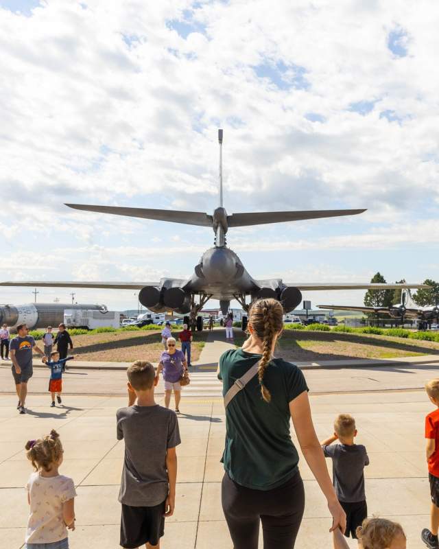family walking behind the b1 plane on display at the south dakota air and space museum