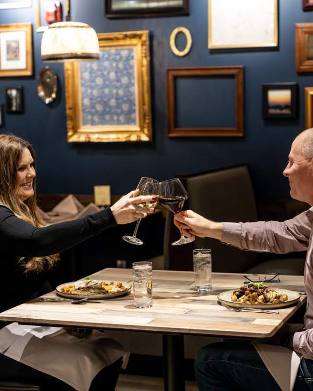couple cheers-ing wine over a meal at tandoor bocado in downtown rapid city, sd