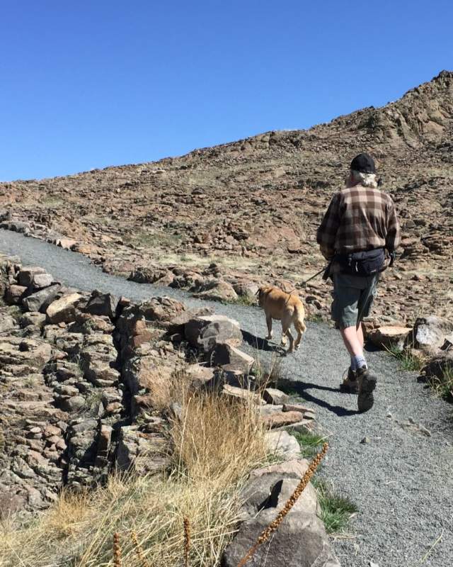 Two people and a dog walk up to lichen peak the highest point on North Table Mountain in Golden, Colorado