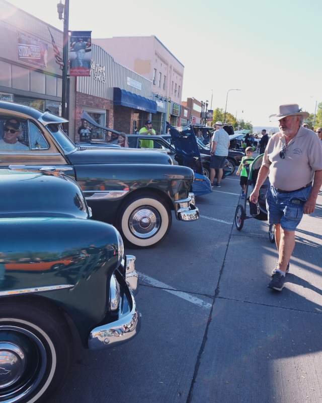 people looking at classic cars parked on the streets of downtown rapid city during the cruiser car show in rapid city, sd