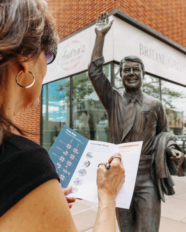 person filling out scavenger hunt in front of Jimmy Carter city of presidents statue in rapid city,sd
