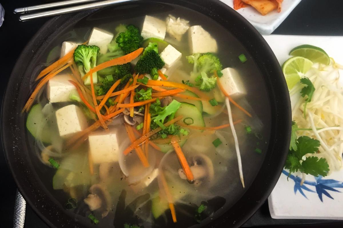 A bowl of tofu pho with toppings on the side.