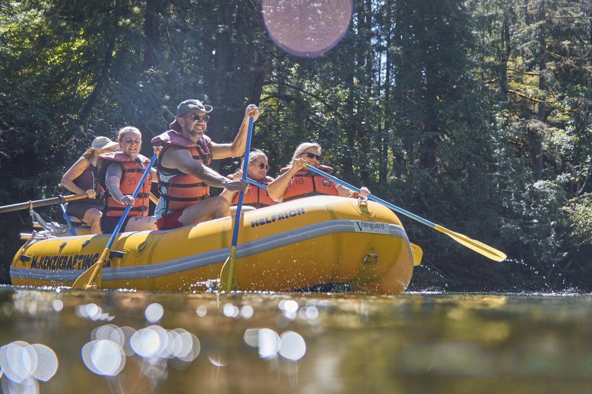 A group of people paddle on a white water raft on the McKenzie River