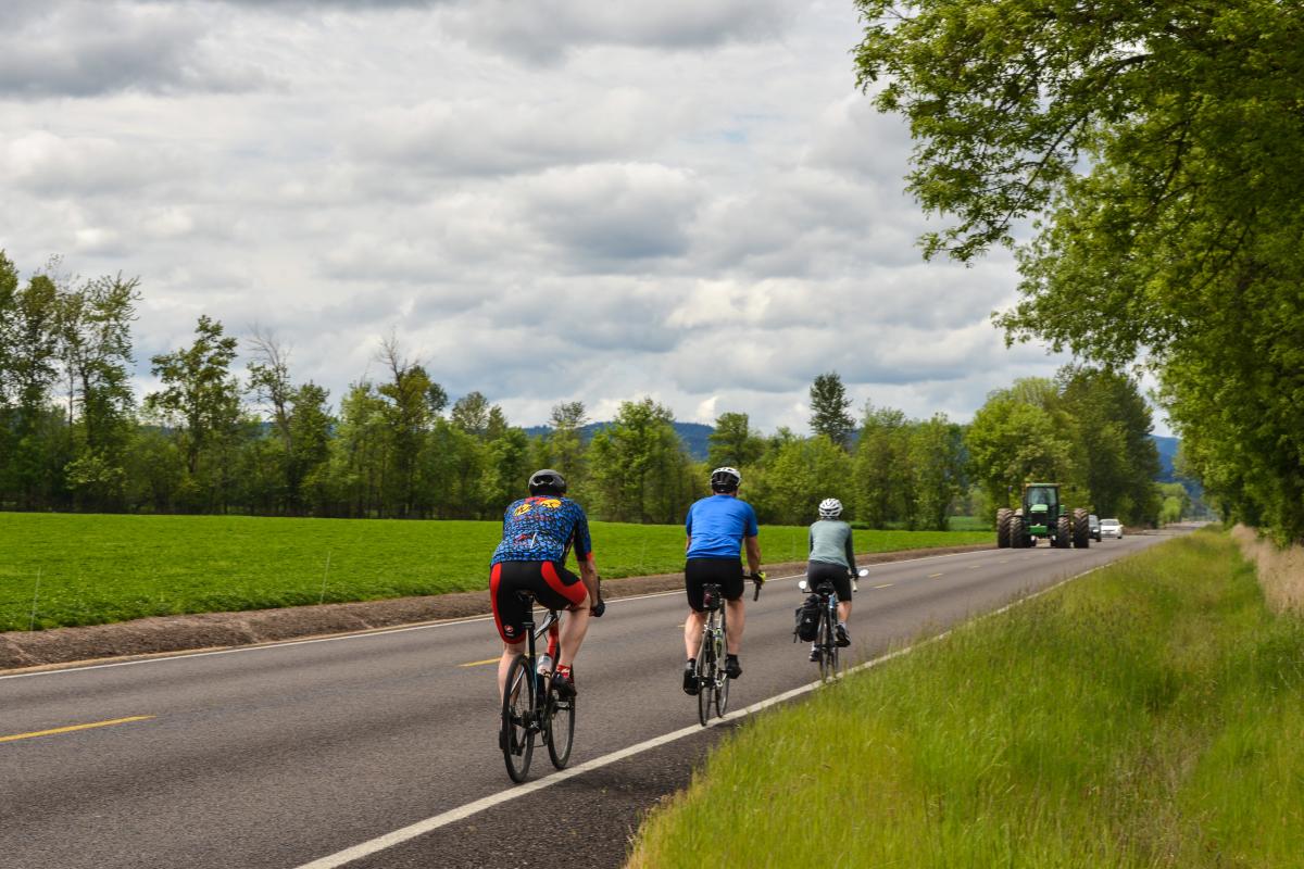 Three cyclists ride along the road in the country near Junction City.