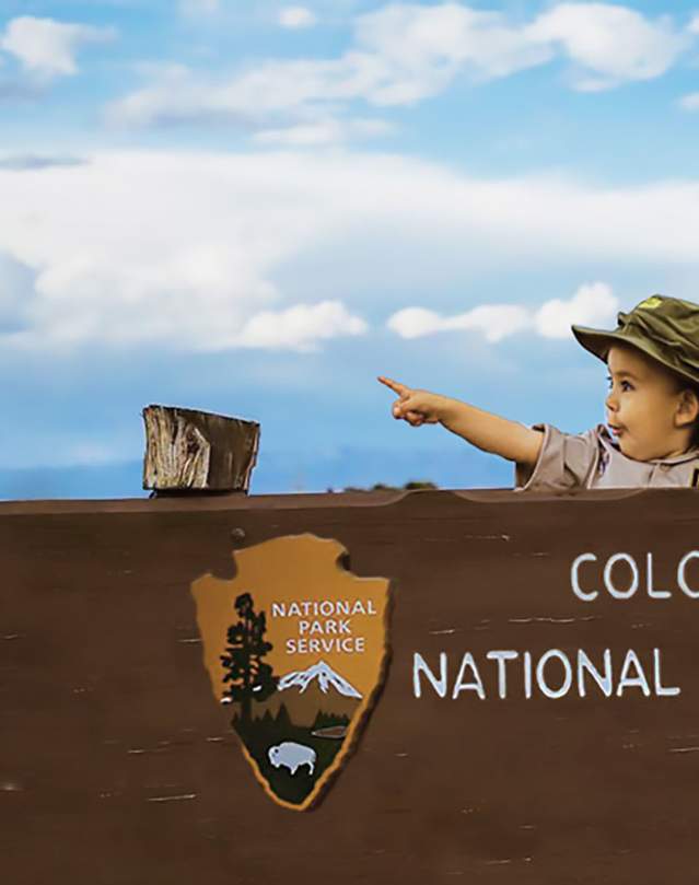 Kid Pointing over the Colorado National Monument Sign