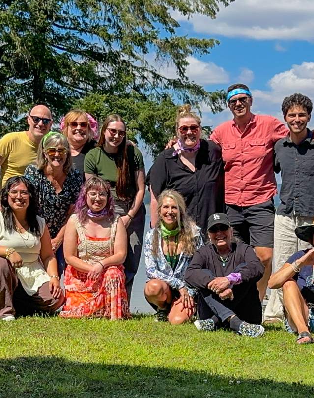 A portion of the staff for Travel Lane County on the grass by Fern Ridge during a team retreat.
