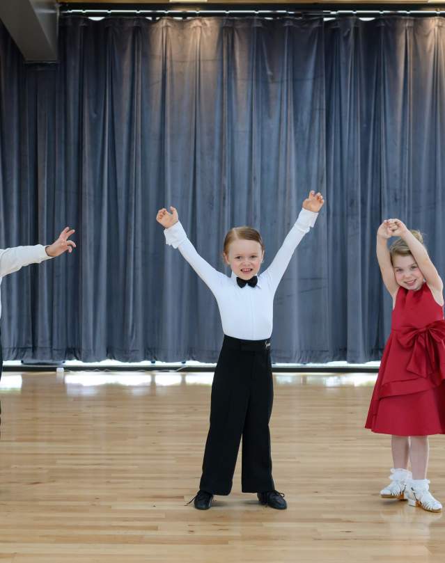 Four children in dress clothes on the ballroom dance floor.