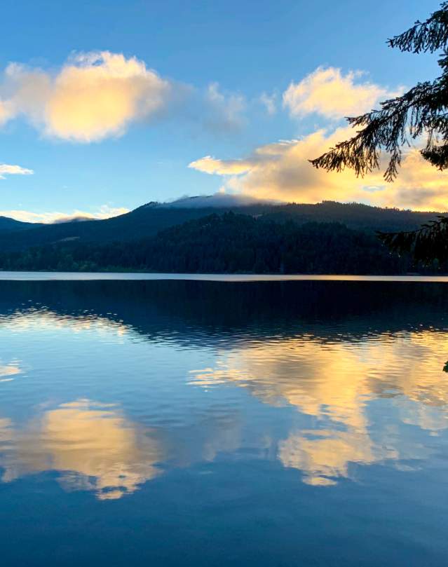 Orange clouds at sunrise over a still lake reflect in the water.