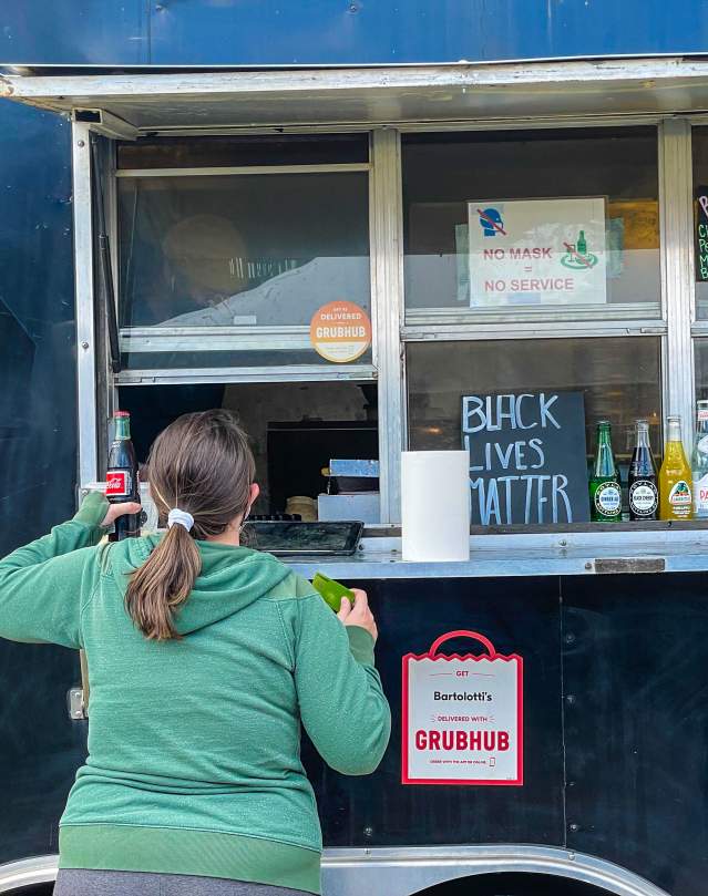 Person ordering at the window of a pizza food truck.